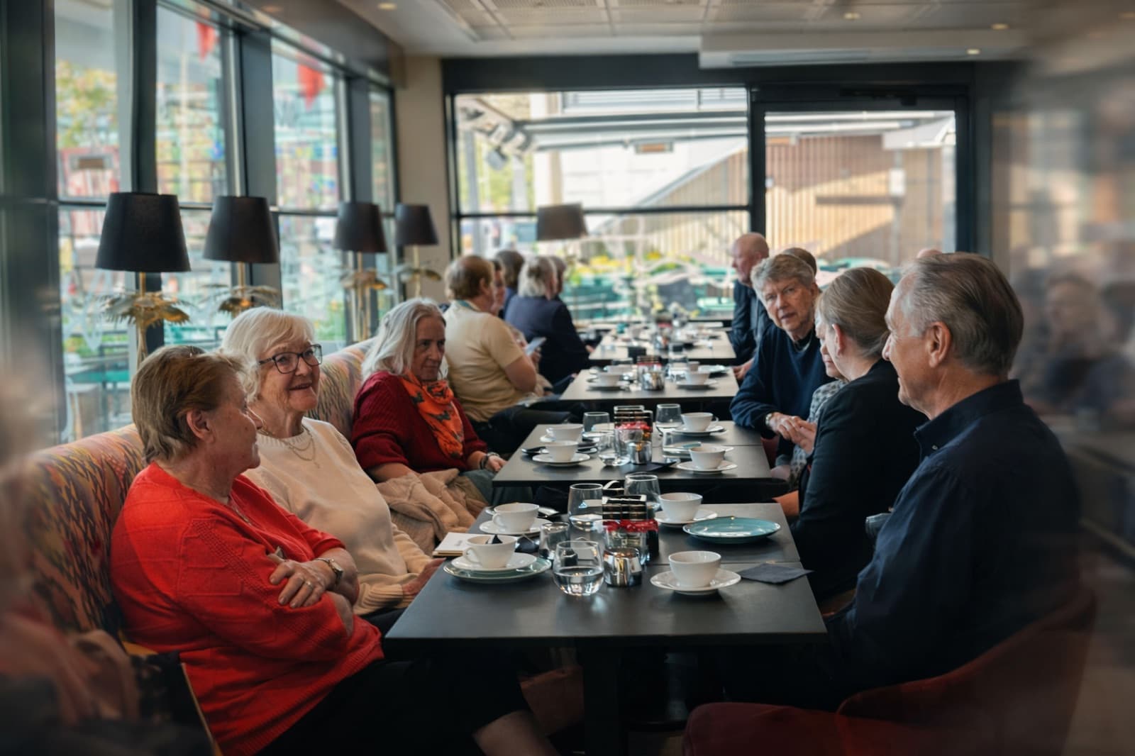 Deltakere rundt bordet på kafé – latter, kaffe og god prat